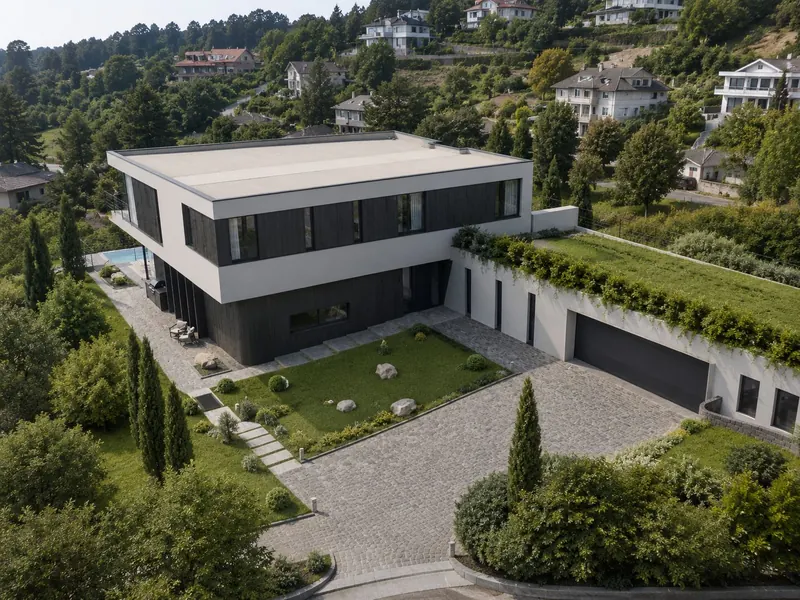 Aerial view of a white and dark timber house on a hillside, with a planted roof over the garage
