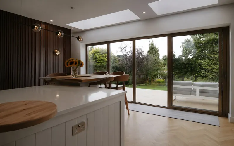 Inside the extension: a kitchen island, slatted walnut wall, rooflights and sliding doors to the garden